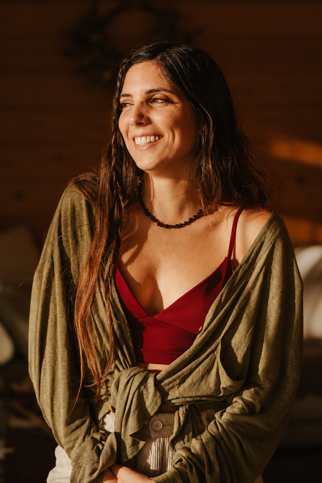 Sofía, the maker of the Moontime Collection, wearing a garnet necklace in warm sunlight
