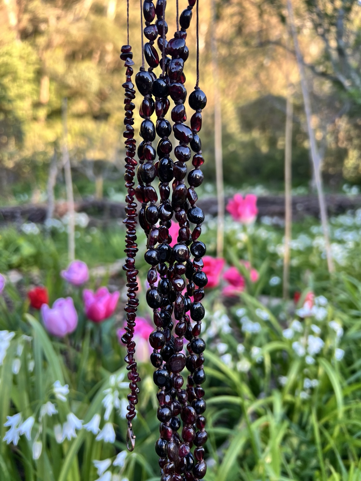 The Spring Equinox garnet adornments hanging among spring flowers