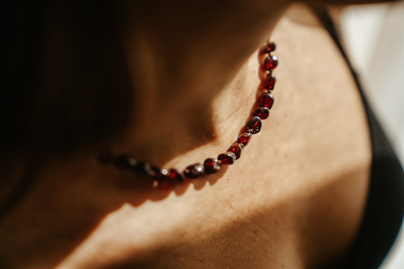 The garnet Moontime necklace resting at the collarbone in afternoon light